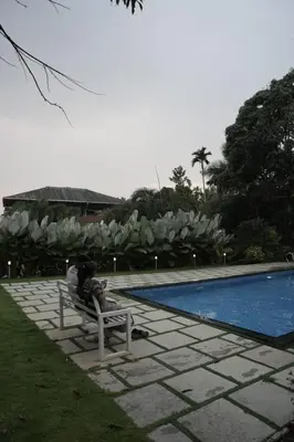 a person sitting on a bench next to a swimming pool at Wayanad Cliff Hotel Apartments in Kalpetta