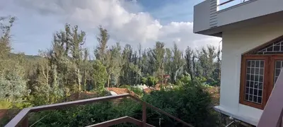 a balcony with a view of a forest of trees at Anya Paradise in Ooty