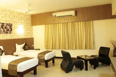 a hotel room with two beds and a table and chairs at Hotel Shiva Grand in Coimbatore