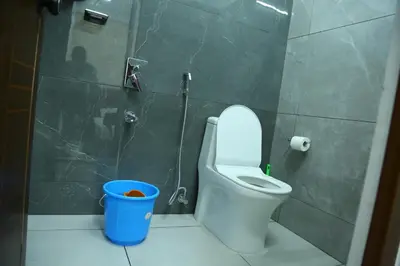 a bathroom with a toilet and a blue trash can at Kurianplackal Residency in Alwaye