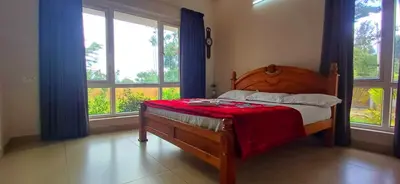 a bedroom with a wooden bed with a red blanket at Wayanad Empire Colonial Villa in Kalpetta