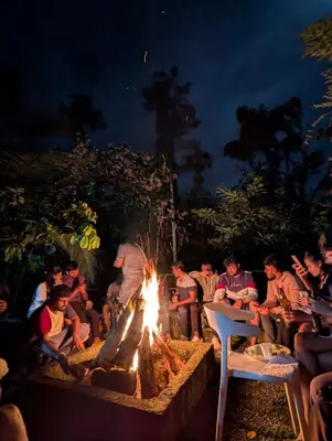 a group of people sitting around a fire at Wayanad Empire Colonial Villa in Kalpetta