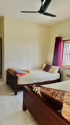 a bedroom with two beds and a ceiling fan at Edenvilla in Vālpārai