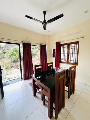 a dining room with a table and chairs and a ceiling fan at Edenvilla in Vālpārai