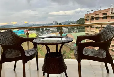 a table and chairs on a balcony with a view at Ponmari Villa in Ooty
