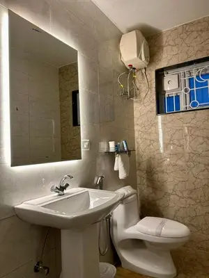 a bathroom with a sink and a toilet and a mirror at Ponmari Villa in Ooty