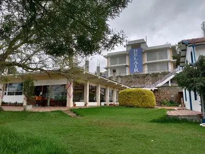 a building with a lawn in front of it at Belair cottages in Kotagiri