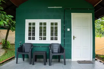 a table and two chairs in front of a green house at The Nest Thattekad in Thattakād