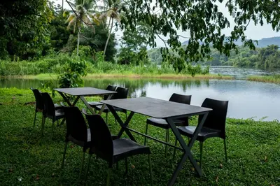 two tables and chairs in front of a lake at The Nest Thattekad in Thattakād