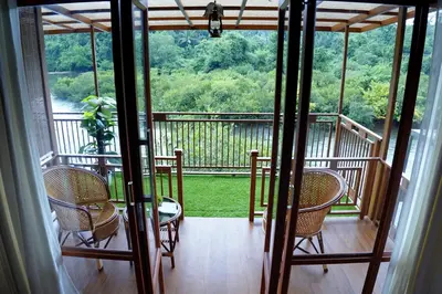 a screened in porch with chairs and a table at Mazhavilkadu ForestResort & Restaurant in Kozhikode