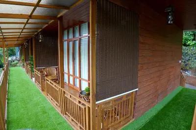 a screened in porch of a house with green grass at Mazhavilkadu ForestResort & Restaurant in Kozhikode