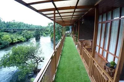 a balcony of a building next to a river at Mazhavilkadu ForestResort & Restaurant in Kozhikode