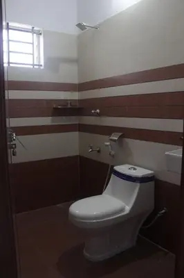 a bathroom with a white toilet and a sink at CITY APARTMENTS in Guruvāyūr