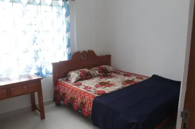 a bedroom with a bed and a table and a window at CITY APARTMENTS in Guruvāyūr