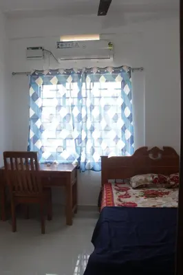 a bedroom with a table and a chair and a window at CITY APARTMENTS in Guruvāyūr