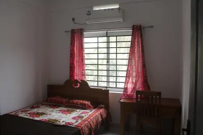a bedroom with a bed and a window with red curtains at CITY APARTMENTS in Guruvāyūr