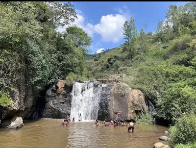 a group of people in the water near a waterfall at JDP Villa 2 Bhk House in Ooty