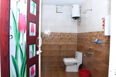 a bathroom with a toilet and a shower with pink flowers at JDP Villa 2 Bhk House in Ooty