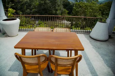 a wooden table and chairs on a patio at Maayaa riverside villa by KPM Tripenta in Attappādi