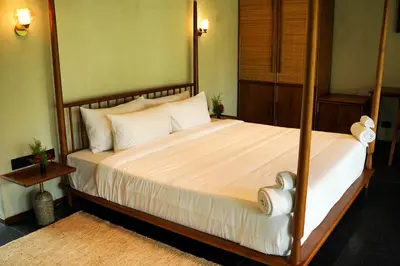 a bedroom with a large bed with white sheets and pillows at Maayaa riverside villa by KPM Tripenta in Attappādi