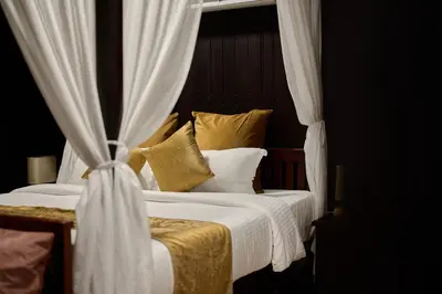 a bedroom with a white bed with curtains and pillows at Maliekal Heritance Cherai Beach Cochin in Cherai Beach