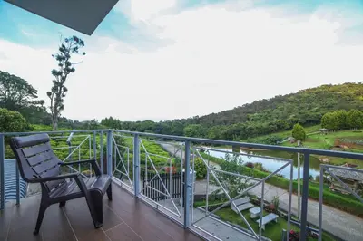 a balcony with a chair and a view of a river at Kalpavriksha 4BR Luxury Villa - Xplore Indo in Kotagiri