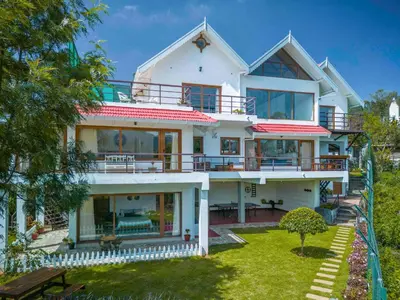 a large white house with large windows and a yard at amã Stays & Trails - Werifesteria, Coonoor in Coonoor