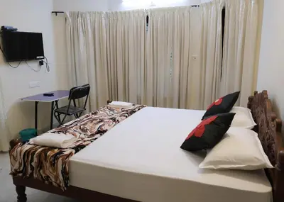 a bedroom with a bed with pillows and a table at Malpans Mansion in Nedumbassery