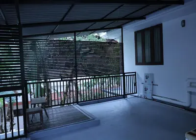 a room with a balcony with wooden blinds and a chair at Malpans Mansion in Nedumbassery