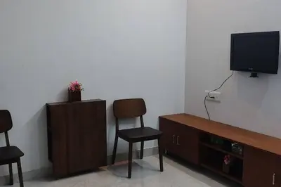 a living room with two chairs and a television at Kailash Guest Home in Mysore