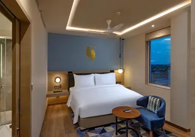a hotel room with a bed and a chair and a window at O by Tamara Coimbatore in Coimbatore