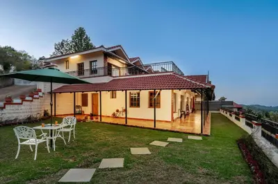 a house with a table and chairs in the yard at StayVista at 5 Rooms at The West Wind - Ooty Comp Breakfast in Ooty