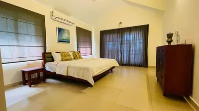 a bedroom with a bed and a dresser and a window at Seagrove Villa in Kappad