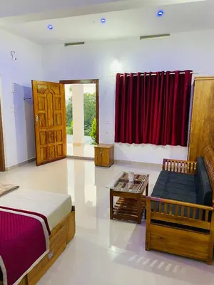 a room with a bed and a couch and a table at Flowers Villa in Ambalavayal