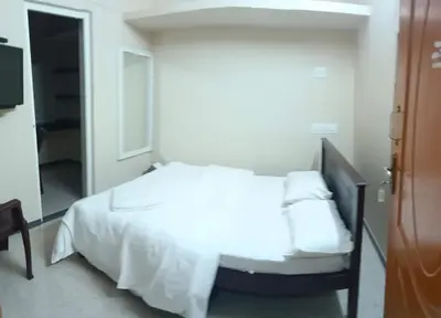 a bedroom with a bed with white sheets and pillows at KUKAL CASTLE in Tiruppūr