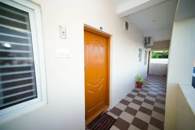 a hallway with a brown door and a checkered floor at KUKAL CASTLE in Tiruppūr