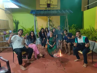 a group of people sitting around a fire at Shanthi Villa in Coonoor