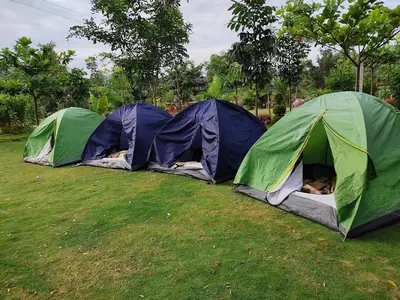 a group of three tents in a field at Kaadgal Resort in Kanakapura