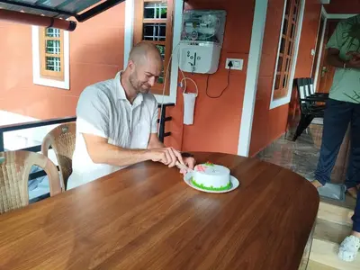 a man cutting a cake on top of a table at Bhuvanam homestay in Kalpetta