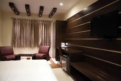 a hotel room with a bed and a flat screen tv at SBS Grand in Coimbatore