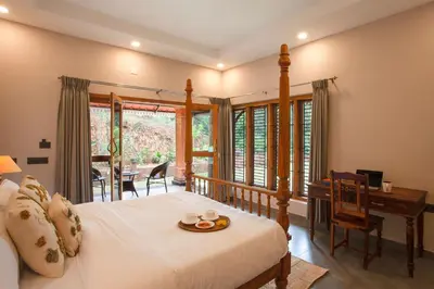 a bedroom with a bed with a table and a desk at StayVista at Regal Retreat 5BR - Big Villa with Pvt Pool in Wayanad