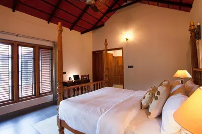 a bedroom with a large bed in a room with windows at StayVista at Regal Retreat 5BR - Big Villa with Pvt Pool in Wayanad