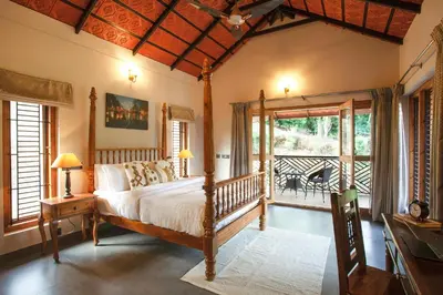 a bedroom with a bed and a balcony at StayVista at Regal Retreat 5BR - Big Villa with Pvt Pool in Wayanad