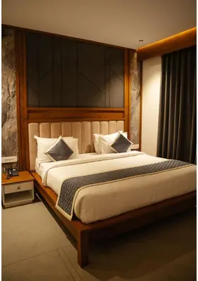 a bedroom with a large bed with a wooden headboard at RITZ AVENUE LUXURY HOTEL in Mahe