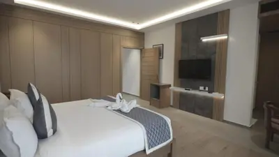 a bedroom with a white bed and a flat screen tv at RITZ AVENUE LUXURY HOTEL in Mahe