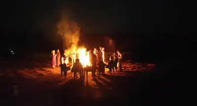 a group of people standing around a fire at night at Spicy Nest Resort in Pinangode