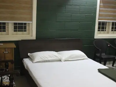 a bed with white pillows in a room with green walls at San Unik Homestay in Nilambūr