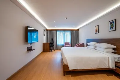 a hotel room with a bed and a desk at Lilac Hotel Guruvayur in Guruvāyūr
