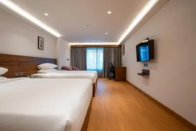 a hotel room with two beds and a television at Lilac Hotel Guruvayur in Guruvāyūr