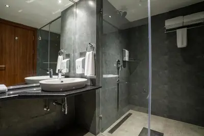 a bathroom with two sinks and a glass shower at Lilac Hotel Guruvayur in Guruvāyūr